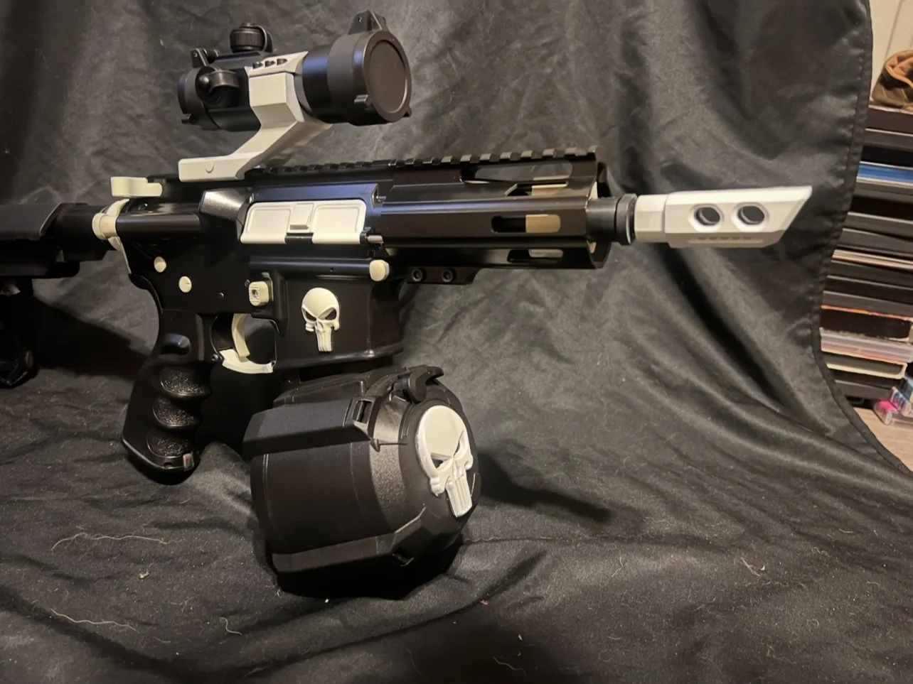 Black AR-15 pistol with white Cerakote accents and Punisher skulls on the receiver and drum magazine by Tattoo Tactical
