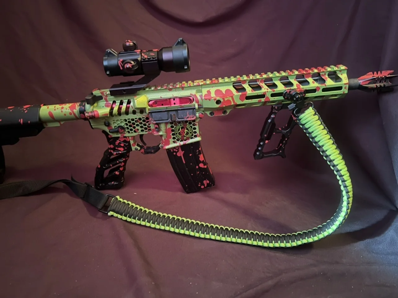 Outbreak custom Cerakote AR-15 with a 10-inch barrel, lime green with red splatter, black honeycomb grip and matching paracord sling by Tattoo Tactical