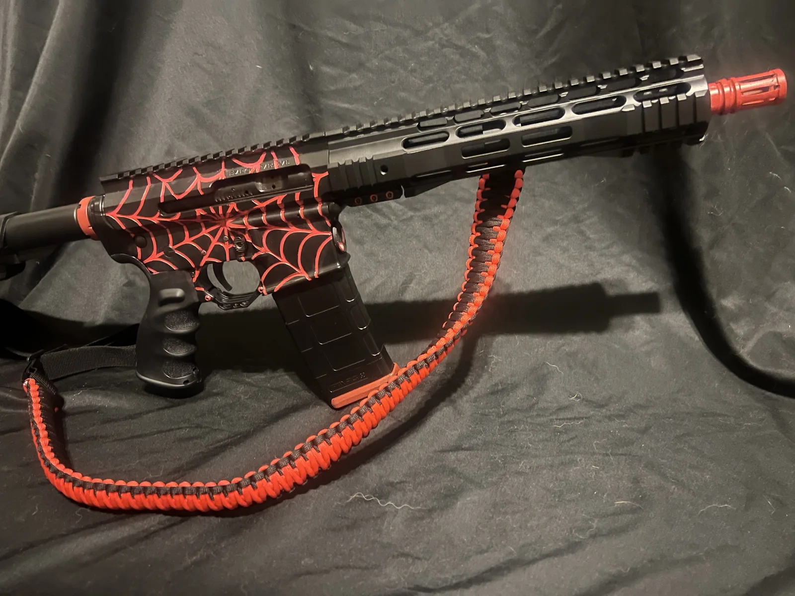 Black AR-15 pistol with a red spider web Cerakote pattern on the receivers by Tattoo Tactical